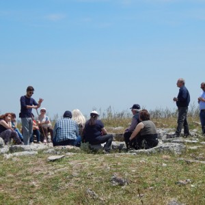 sei-su-immagine-raffigurante-luca-mentre-spiega-il-villaggio-neolitico-di-murgia-timone-ad-un-gruppo-di-persone-con-disabilità-psichica